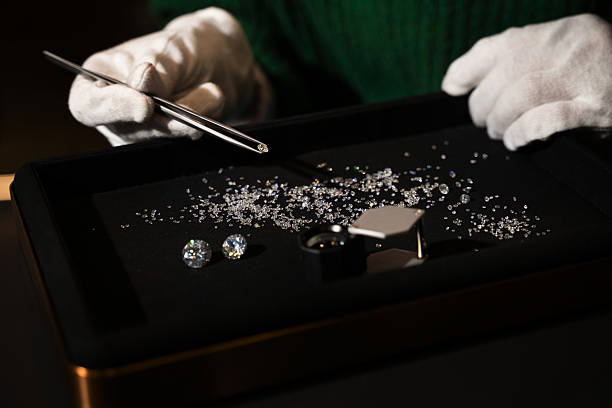 Gemologist holds a small diamond with tweezers for precise inspection and sorting